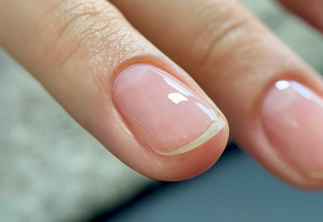 Gros plan sur un ongle nude brillant, résultat d'une pose Grace Manucure